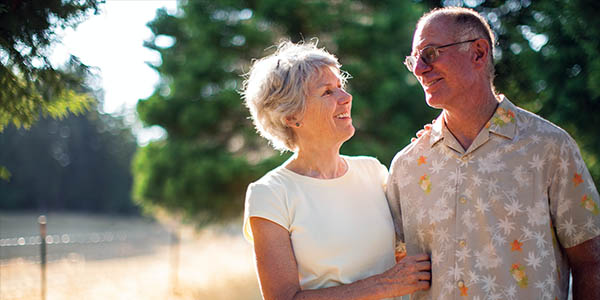 old, male and female couple linking arms while smiling
